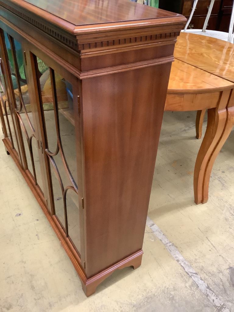 A reproduction mahogany three door bookcase, width 135cm depth 33cm height 116cm